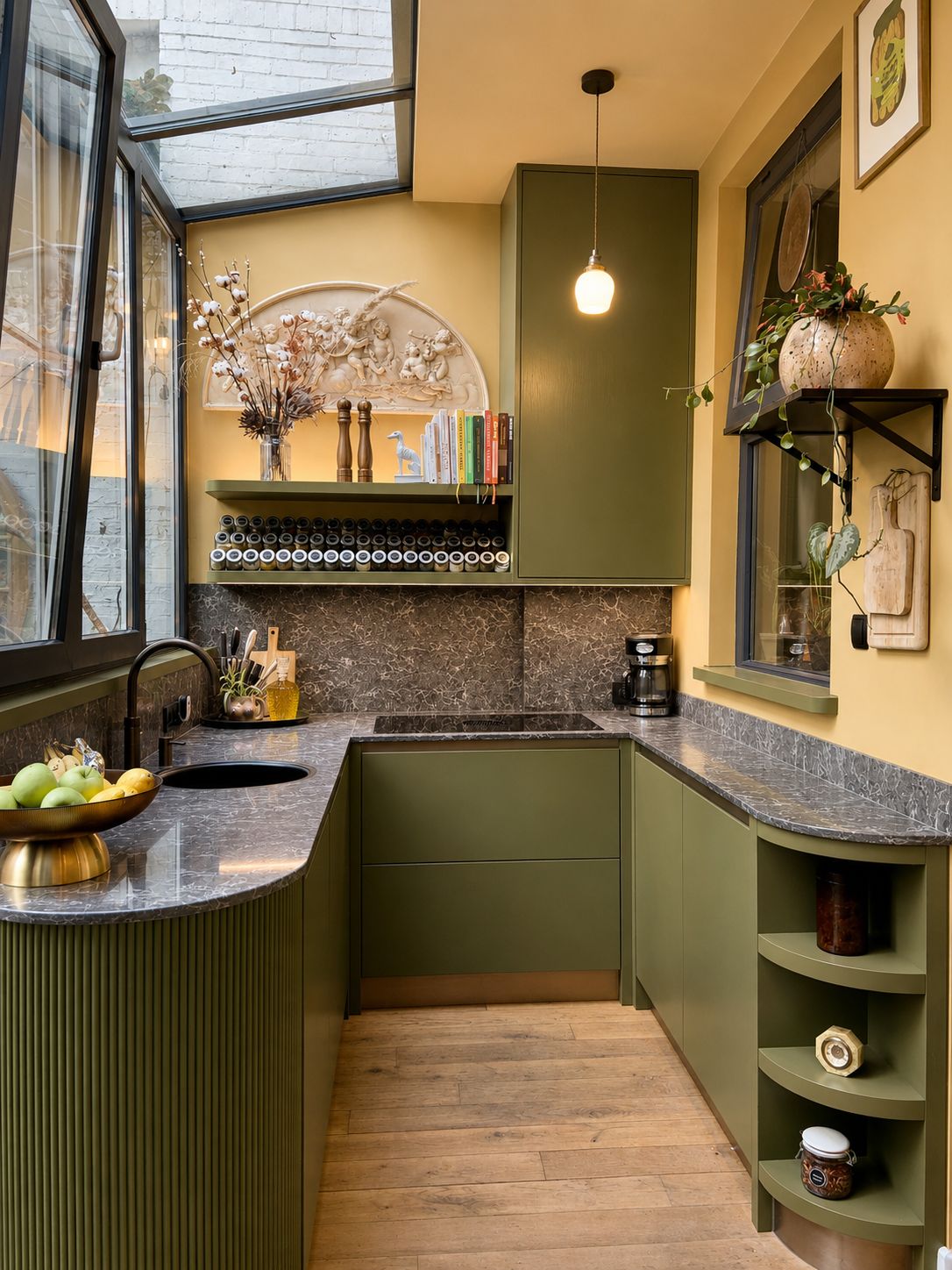 Olijfgroene keuken van Roxy Jones Design met marmeren blad, geribbeld kookeiland en okergele wanden onder een glazen dak